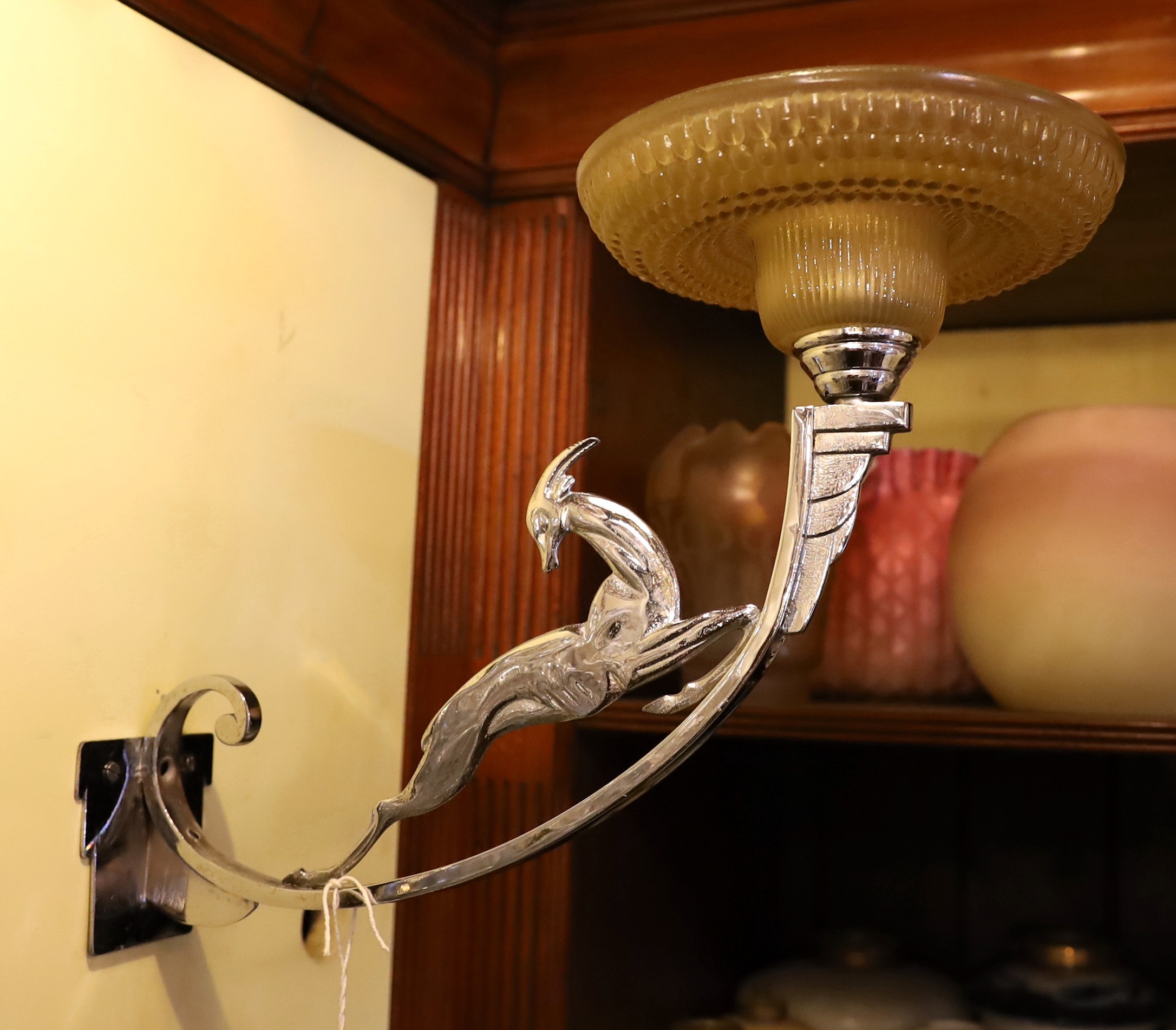 A French Art Deco nickel plated wall light with moulded glass shade and antelope stem, height 30cm. depth 35cm